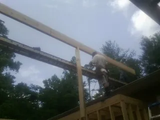 Carpenter setting a ridge beam over a new addition frame — Ice Dam Removal by Roofing Brothers in Goldston