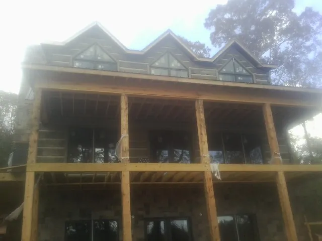 Dormers and porch framing on a large log home under construction — Roof Coating work by our crew in Goldston