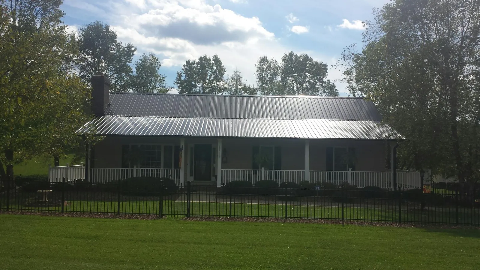 Gray metal roof on a brick ranch with a full width front porch — Gutter Guard Installation work by our crew in Goldston