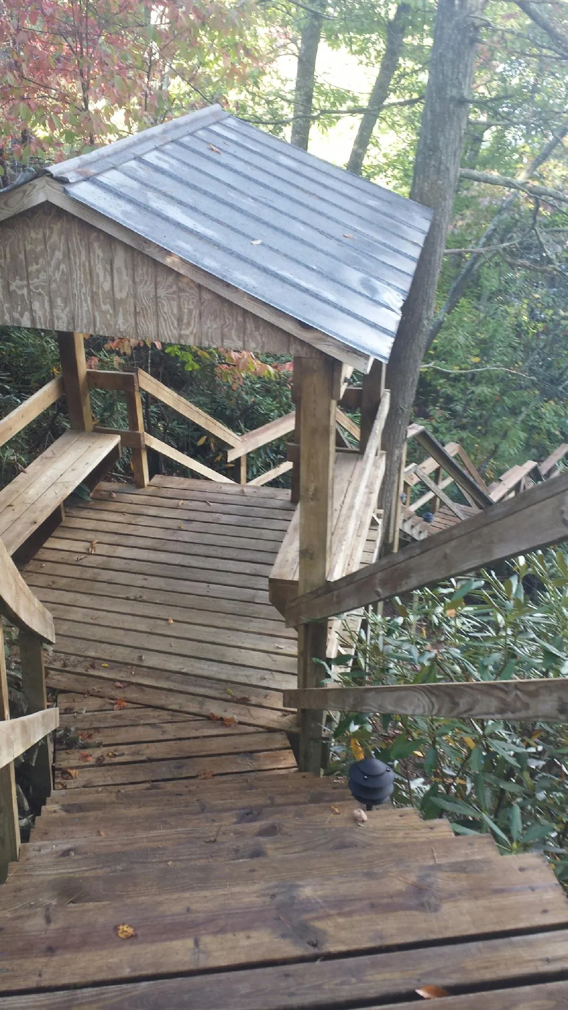 Metal roofed shelter over wooden steps on a wooded walkway — Skylight Repair & Installation work by our crew in Goldston