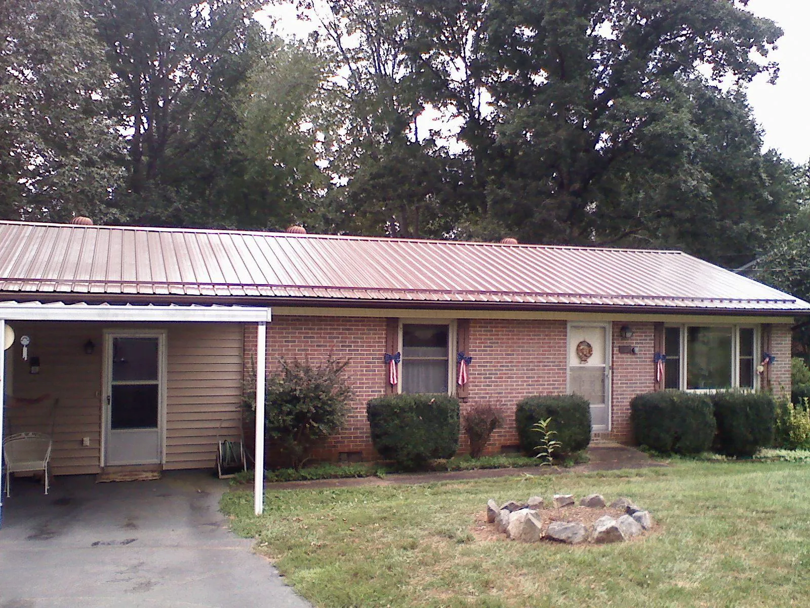Bronze metal roof and carport on a brick ranch home — Roof Repair work by our crew in Goldston