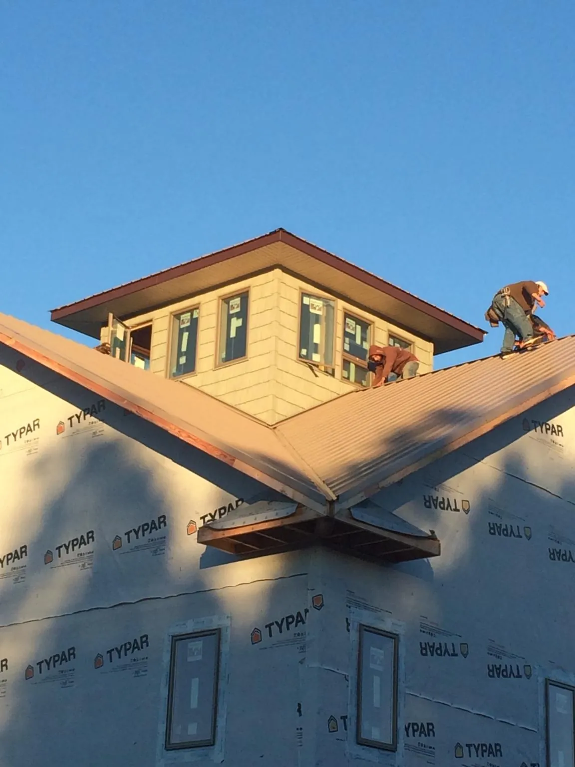 Roofers working around a rooftop cupola on a new metal roof at sunset — Roof Waterproofing in Goldston by Roofing Brothers